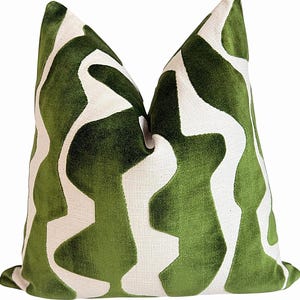 May include: A square throw pillow featuring a bold, abstract pattern of deep green velvet shapes set against a contrasting off-white textured fabric background. The design consists of fluid, organic vertical lines that create a repeating motif.