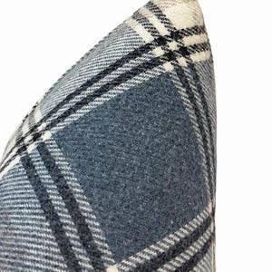 Pu&ograve; includere: Primo piano di un cuscino a quadri blu e bianco. Il cuscino presenta un classico motivo a quadri nelle tonalit&agrave; del blu, bianco e nero. Il tessuto sembra essere un materiale morbido e tessuto.