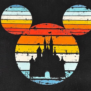 May include: Black graphic featuring a silhouette of a castle within a Mickey Mouse head shape. The design has a retro sunset color scheme of orange, yellow, and blue stripes, with a distressed, vintage look.