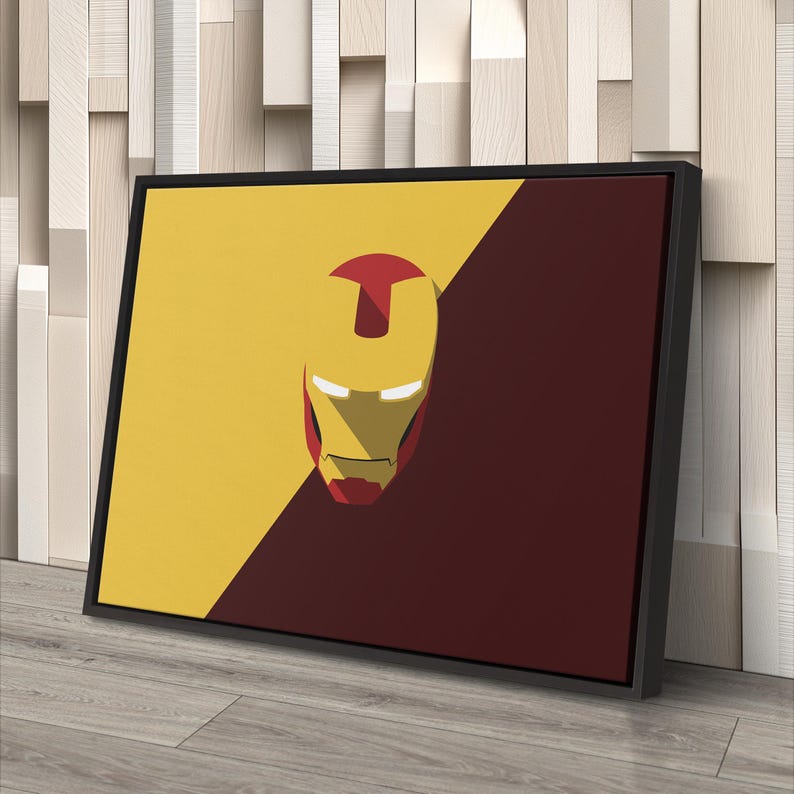 May include: Framed canvas art featuring a minimalist Iron Man helmet design. The artwork is divided diagonally, with a yellow and maroon color scheme. The Iron Man helmet is in the center, with a red top and gold face.