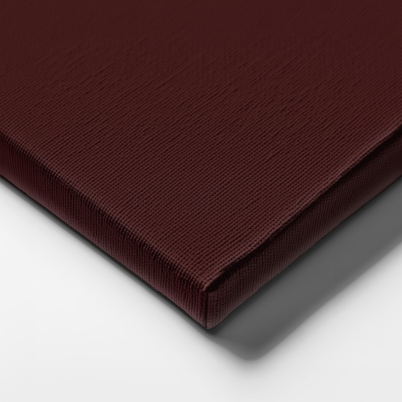 May include: Close-up of a burgundy canvas with a textured surface. The canvas is stretched over a wooden frame, with a visible corner and edge. The color is a deep, rich shade of red-brown.