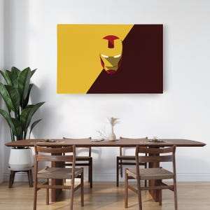 May include: A rectangular canvas art piece featuring a minimalist Iron Man mask design. The artwork is split diagonally, with a yellow and maroon color scheme. The Iron Man mask is red and gold.