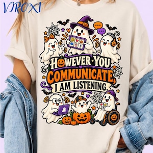 Puede incluir: Una camiseta de color crema con un gráfico de varios fantasmas de dibujos animados comunicándose de diversas formas. El texto dice: "HOWEVER YOU COMMUNICATE, I AM LISTENING." El diseño incluye calabazas, telarañas y murciélagos.