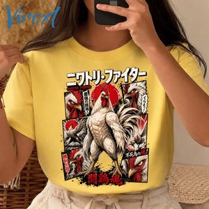May include: A bright yellow t-shirt featuring a graphic print of a muscular rooster in a manga-inspired style. The design includes multiple panels of rooster heads, Japanese text, and a red sun motif, creating a bold, comic-book aesthetic.