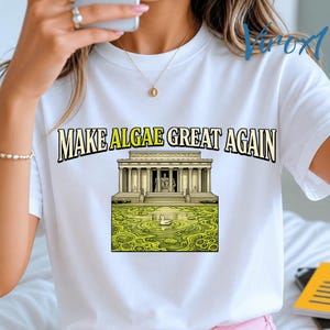 Könnte beinhalten: Ein weißes T-Shirt mit kurzen Ärmeln und einem Grafikdruck des Lincoln Memorials, das von grünen Algen im Reflexionsbecken umgeben ist. Der Text "MAKE ALGAE GREAT AGAIN" ist in schwarzen und gelben Buchstaben über der Abbildung gedruckt.