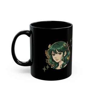 May include: Black ceramic mug with a detailed illustration of a woman with green hair. The artwork includes stars and botanical elements. The mug has a curved handle and a glossy finish, suitable for hot drinks.