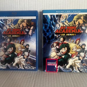 May include: Two My Hero Academia: Two Heroes movie cases, one in a blue plastic Blu-ray case and one with a cardboard slipcover. Both feature the film title, the text Full Length Feature Film, and an illustration of various anime characters.