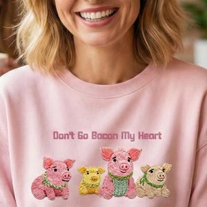 Könnte beinhalten: Hellrosa Sweatshirt mit dem Text "Don't Go Bacon My Heart" und einer Grafik von vier Cartoon-Schweinen. Das Bild zeigt eine Gruppe von Frauen, die in einem Café lachen und Kaffee trinken.