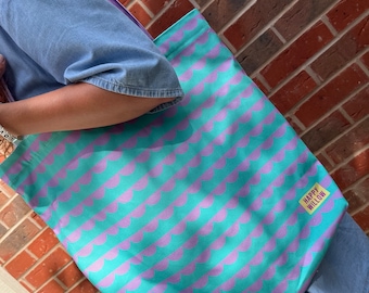 May include: A teal tote bag with a purple and teal geometric pattern. The bag has a yellow label that says "Happy Willow".