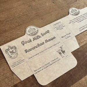 Puede incluir: Una taza de cerámica blanca con un asa negra y el texto "But First, Coffee" en negrita negra. La taza está llena de un líquido oscuro, probablemente café, y se encuentra sobre una superficie de color claro.