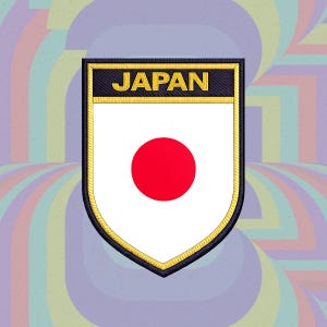 Puede incluir: Un parche bordado en forma de escudo con fondo blanco y un círculo rojo central. La sección superior contiene la palabra JAPAN en letras mayúsculas amarillas sobre un fondo negro, todo bordeado por un grueso borde cosido en amarillo y negro.