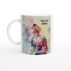 May include: White ceramic mug with a watercolour illustration of a woman in traditional dress, and the text "FALLAS 2026". The design includes a colourful, abstract background. The mug has a curved handle.