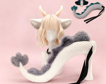 May include: A fantasy-themed costume set featuring a white and gray dragon tail, a matching headpiece, and a wig with deer-like ears and antlers. The tail is approximately 30 inches long and has black straps.