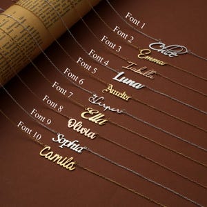 May include: A collection of personalized name necklaces in various fonts. Each necklace features a delicate chain and a name pendant. The names include Chloe, Emma, Isabella, Luna, Amelia, Harper, Ella, Olivia, Sophia, and Camila.
