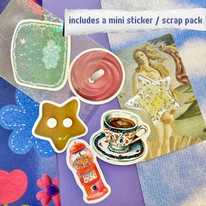 May include: A collection of colorful stickers and embellishments, including a red button, a star-shaped sticker, and a gumball machine. The text "includes a mini sticker / scrap pack" is visible.