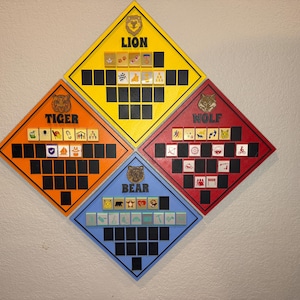 May include: A wooden board game with four diamond-shaped sections in yellow, orange, red, and blue. Each section features a different animal name: Lion, Tiger, Wolf, and Bear. The game boards have small square spaces and illustrated game pieces.