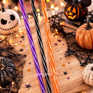 May include: Three reusable drinking straws featuring a diagonal spiral pattern. One straw is purple with a silver spiral, one is black with a silver spiral, and one is orange with a white spiral. Each straw includes a clear silicone ring at the base.