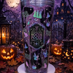 May include: A clear tumbler filled with purple glitter and liquid, featuring holographic decals of the Sanderson Sisters, cauldrons, cats, and witch hats. The central label reads The Sanderson Sisters Hocus Pocus Apothecary Est 1693.