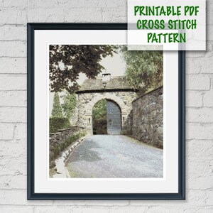 May include: Framed cross stitch pattern print featuring a stone archway with a gated entrance and a pathway leading towards it. The print includes the text "PRINTABLE PDF CROSS STITCH PATTERN" in green.