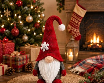 May include: A crochet gnome figurine featuring a tall, pointed red hat with a white snowflake applique and a white pom-pom at the tip. The gnome has a beige nose, a long white beard, a gray body, red mittens, and red feet, standing upright.