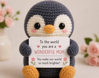May include: A crocheted penguin toy in grey, white, and orange, holding a card with text. The card says "To the world you are a WONDERFUL MOM. You make our world so much brighter!" with pink hearts and flowers.