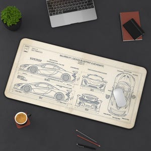 May include: A rectangular desk mat featuring a technical blueprint of a McLaren P1. The design includes side, front, rear, and top views of the vehicle with technical specifications, dimensions, and labels printed in black on a light beige background.