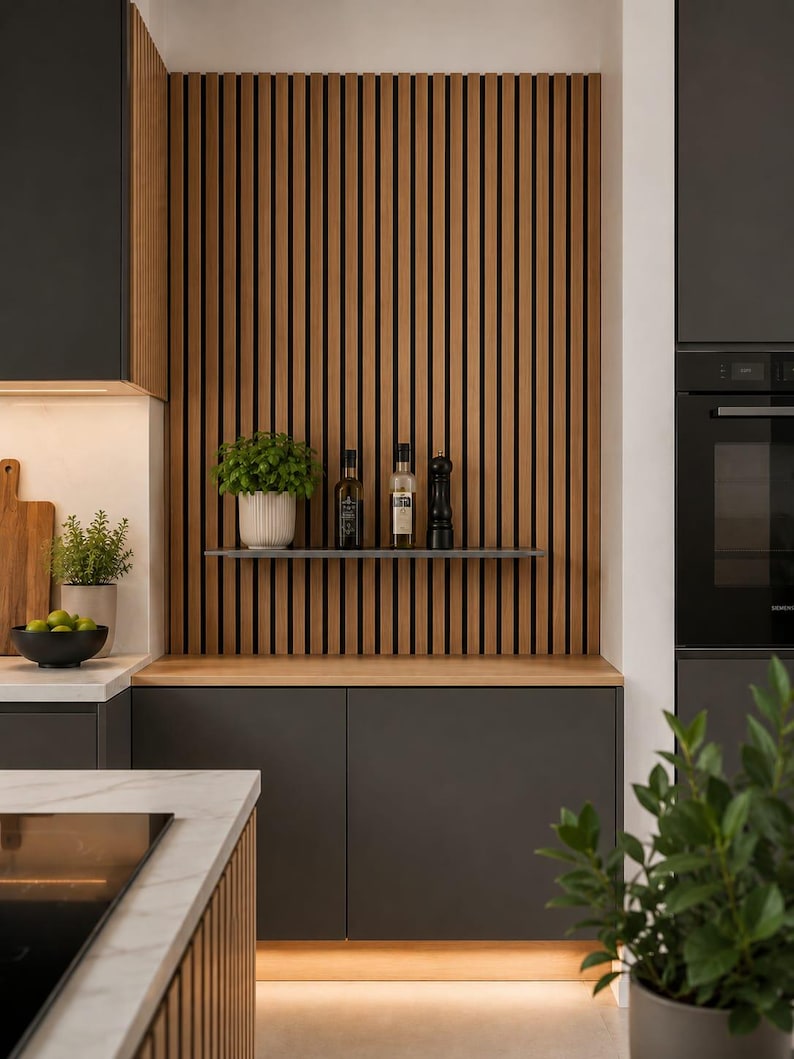 May include: A kitchen wall feature composed of vertical light brown wooden slats with black gaps, featuring a floating shelf holding a white ribbed pot with a green plant, two glass bottles with liquid, and a black pepper mill above dark cabinets.