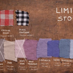 Flat lay of twelve linen fabric swatches on wood, labeled with color and weight. Top row: Cottage Thyme, Cottage Rose, Black Gingham (medium weight, checkered). Bottom row: Grey (heavier), Taupe, Sand, Dewy Rose, Rose Geranium, Lavender, Charcoal, Blueberry, Dusty Sky (medium weight solids). “LIMITED STOCK” and OEKO-TEX 100 Certified text included. Fabric palette belongs to Knocknocklinen. 2026-06-09