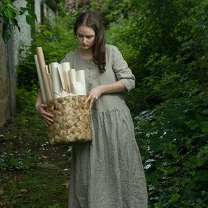 A girl with a basket of drawings by a cottage in a secluded garden by knockknocklinen