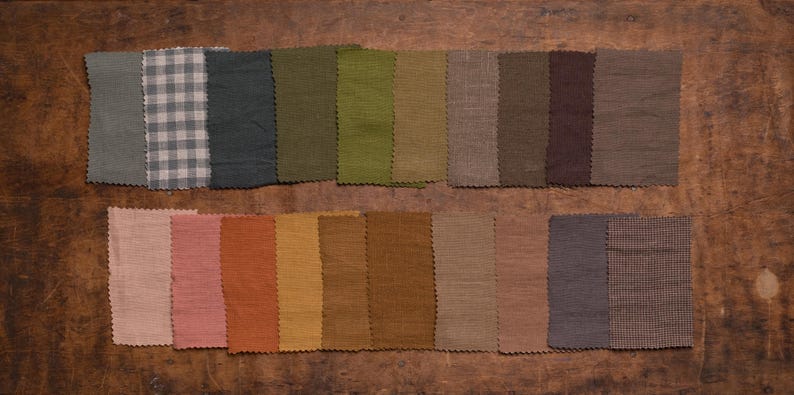 KnockKnockLinen fabric sample set—20 linen swatches in brown, green, and gray tones; solids plus gingham and houndstooth; pinked edges arranged in two rows, flat lay on a wooden surface. Fabric samples / swatch book.