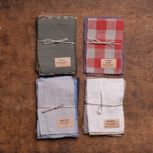 KnockKnockLinen fabric samples—four bundles of medium-weight linen swatches tied with string: Cactus green, Cottage Rose red-white gingham, Light Grey, and Off-White; pinked edges, labeled, arranged in a flat lay on a wooden table.