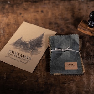 Puede incluir: Un conjunto de muestras de tela en varios tonos de verde y marrón, atadas con una cuerda. Las muestras están etiquetadas como "Cactus" y "Peso medio". La imagen también incluye una tarjeta de papel marrón con el texto "Knock Knock | Atelier | Collection for creative people".