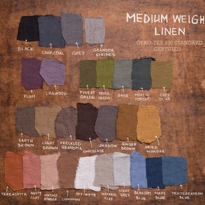 Flat lay of 27 medium weight linen fabric swatches on a wooden surface, each labeled with its color name. Colors range from Black, Plum, Sage, Terracotta to Navy. Includes OEKO-TEX 100 certification note. Fabric palette belongs to Knocknocklinen
