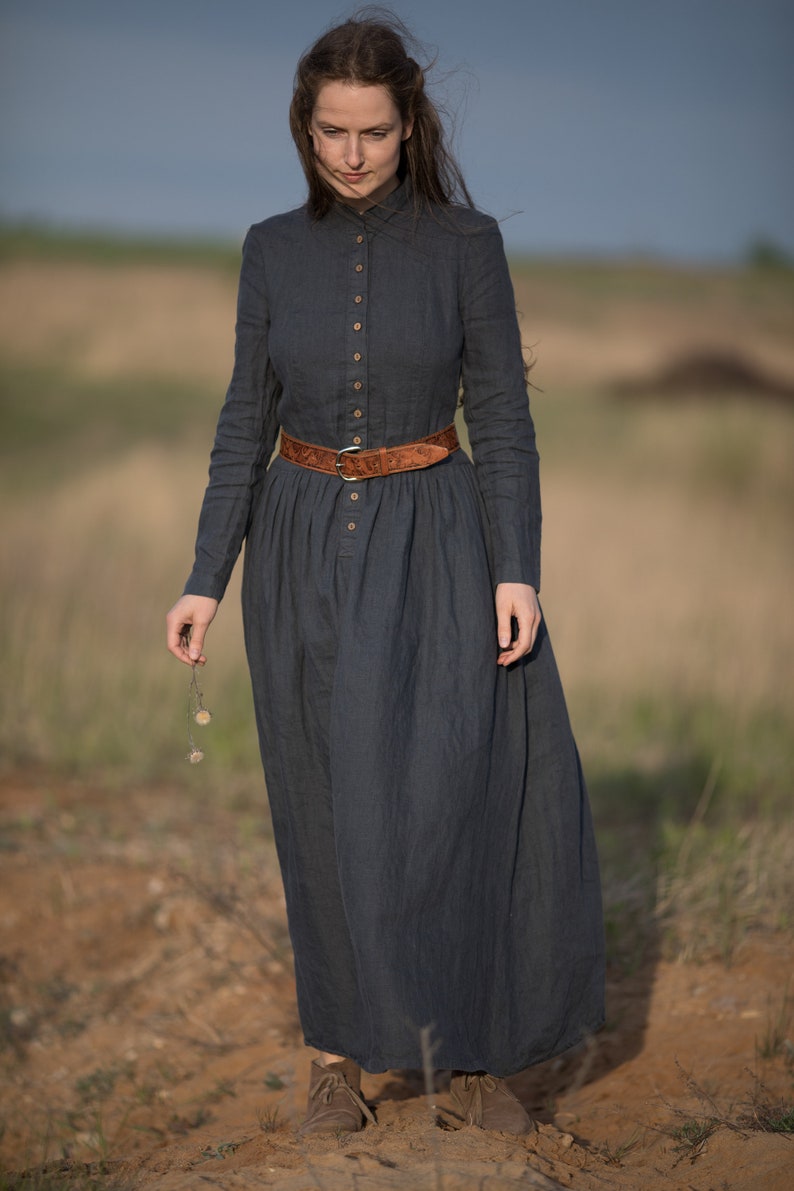 A girl in a Victorian linen dress, gracefully holding a flower.