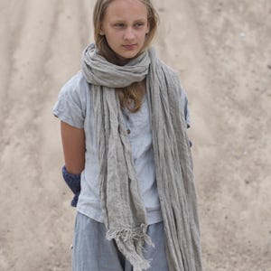 KnockKnockLinen “Silence” short-sleeve linen top—light grey, buttoned front, loose fit—shown on model outdoors with a long natural-flax linen scarf and relaxed linen pants against a sandy backdrop. Linen blouse / buttoned linen top.