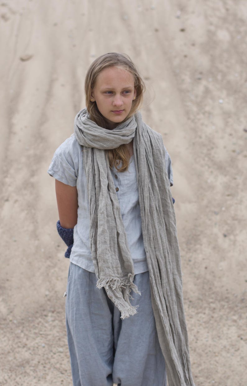 KnockKnockLinen “Silence” short-sleeve linen top—light grey, buttoned front, loose fit—shown on model outdoors with a long natural-flax linen scarf and relaxed linen pants against a sandy backdrop. Linen blouse / buttoned linen top.