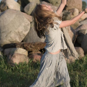 KnockKnockLinen short-sleeve buttoned linen top “Silence” — light grey, round neck, front button placket, loose fit — shown on model outdoors with matching drawstring linen pants and a fringed scarf. Summer linen blouse on model.