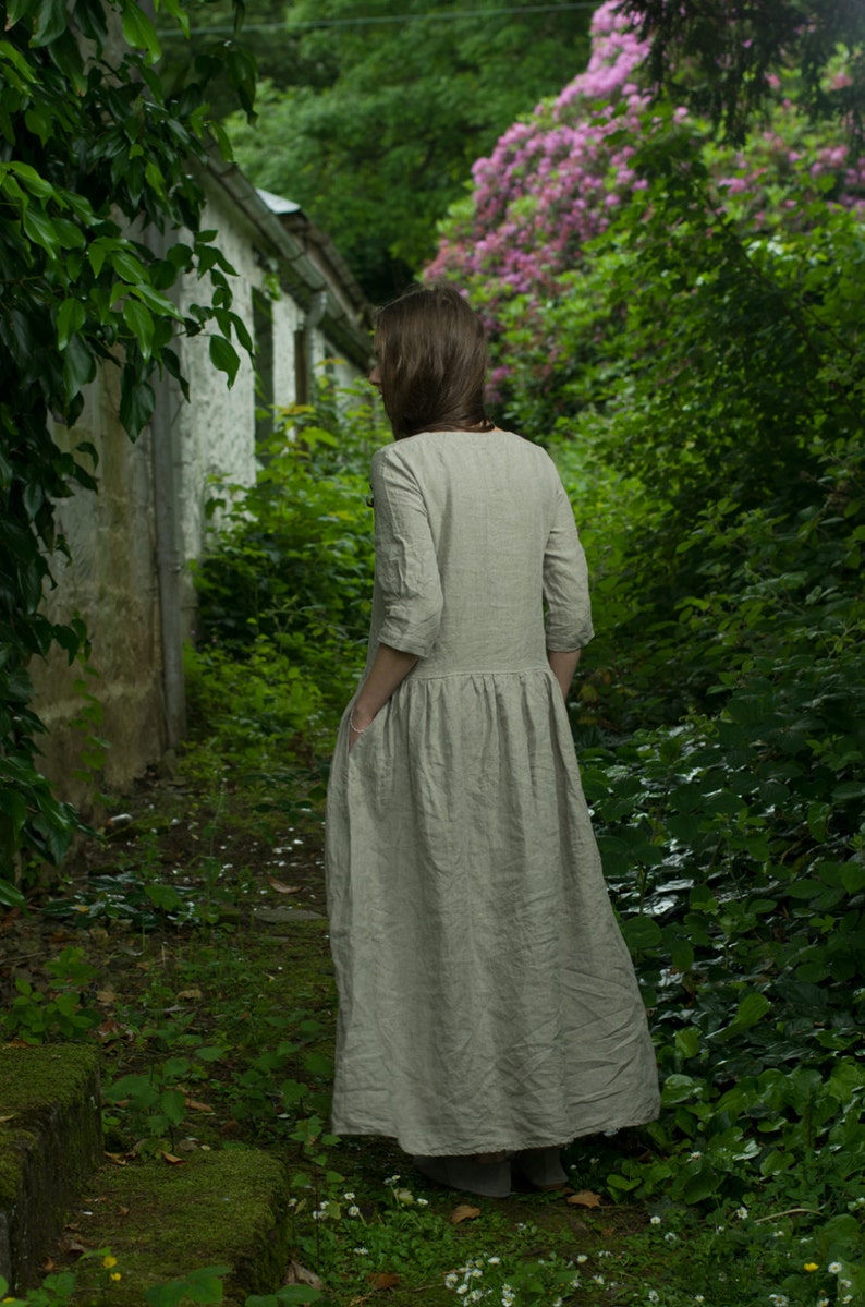 A girl in a linen dress enjoying her time in a secret garden by knockknocklinen