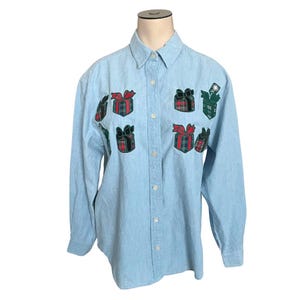 May include: A light blue denim button-down shirt with embroidered plaid gift boxes. The shirt has long sleeves and a classic collar.