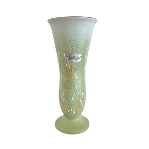 May include: A green ceramic vase with a white and gold speckled design. The vase has a label that reads "Carstens  REPRODUCTION  COLLECTION".