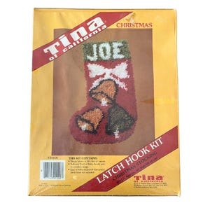 May include: A Christmas stocking latch hook kit by Tina of California. The kit includes a red stocking design with the name "JOE" at the top, white bow, and bell accents. The kit is approximately 16 inches high.