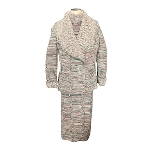 May include: A vintage knit skirt suit in a multi-color yarn. The jacket has a wide shawl collar and long sleeves with rolled cuffs. The skirt is a straight, knee-length style. The color palette includes shades of gray, pink, and green.