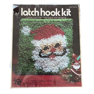 Könnte beinhalten: Ein Vintage-Latch-Hook-Kit mit einem Weihnachtsmann-Design. Das Kit enthält vorgeschnittenes Garn und eine vorgedruckte Leinwand. Die fertige Größe beträgt ca. 30 cm x 43 cm. Die Verpackung trägt den Text "latch hook kit" und "Create Your Own Area Rug or Wall Hanging".
