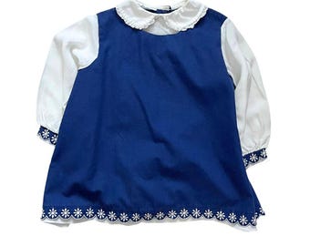 May include: A blue and white dress with a white collar and long sleeves. The dress has a white embroidered daisy trim around the bottom.