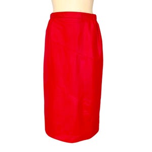 May include: A vibrant red pencil skirt. The skirt is a solid color with a subtle sheen, featuring a tailored fit that gently tapers towards the hem. The skirt has a clean, minimalist design, suitable for various occasions.