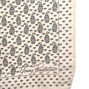 May include: Cream silk scarf featuring a repeating pattern of figures in hats and diamond shapes. The figures are in blue, green, and grey. The scarf has the text "Young Pendleton" in the corner.