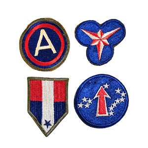May include: Four embroidered patches with military-themed designs. One patch features a large white "A" inside a blue circle with a red border. Another has a red and white star on a blue background. The other two patches have red, white, and blue designs.