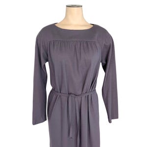 May include: A long-sleeved, gray dress with a scoop neckline and a tie belt at the waist. The dress features a gathered detail across the chest and a simple, elegant design. The dress is displayed on a mannequin.