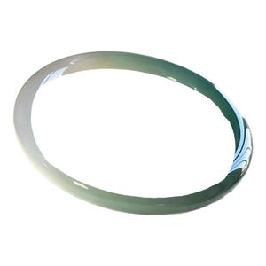 Puede incluir: Una pulsera tipo brazalete circular y lisa hecha de piedra pulida. El accesorio presenta una transición de color degradada, que cambia de un blanco roto translúcido en un lado a un verde bosque profundo y vibrante en el otro.