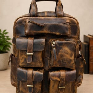 May include: A brown distressed leather backpack featuring a top handle, a horizontal zipped pocket, and four front pockets with flap closures secured by metal buckles. The bag includes two side pockets and vertical zip details on the front.